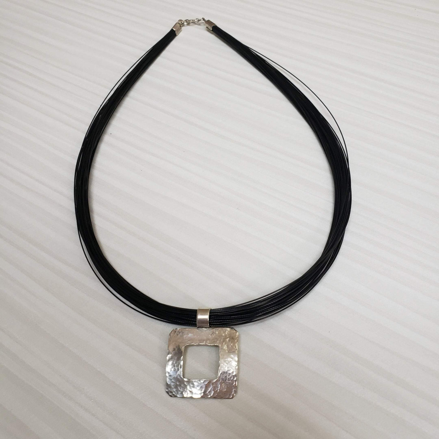 Silver hammered pendant on a multi strand black cord - LB Designs